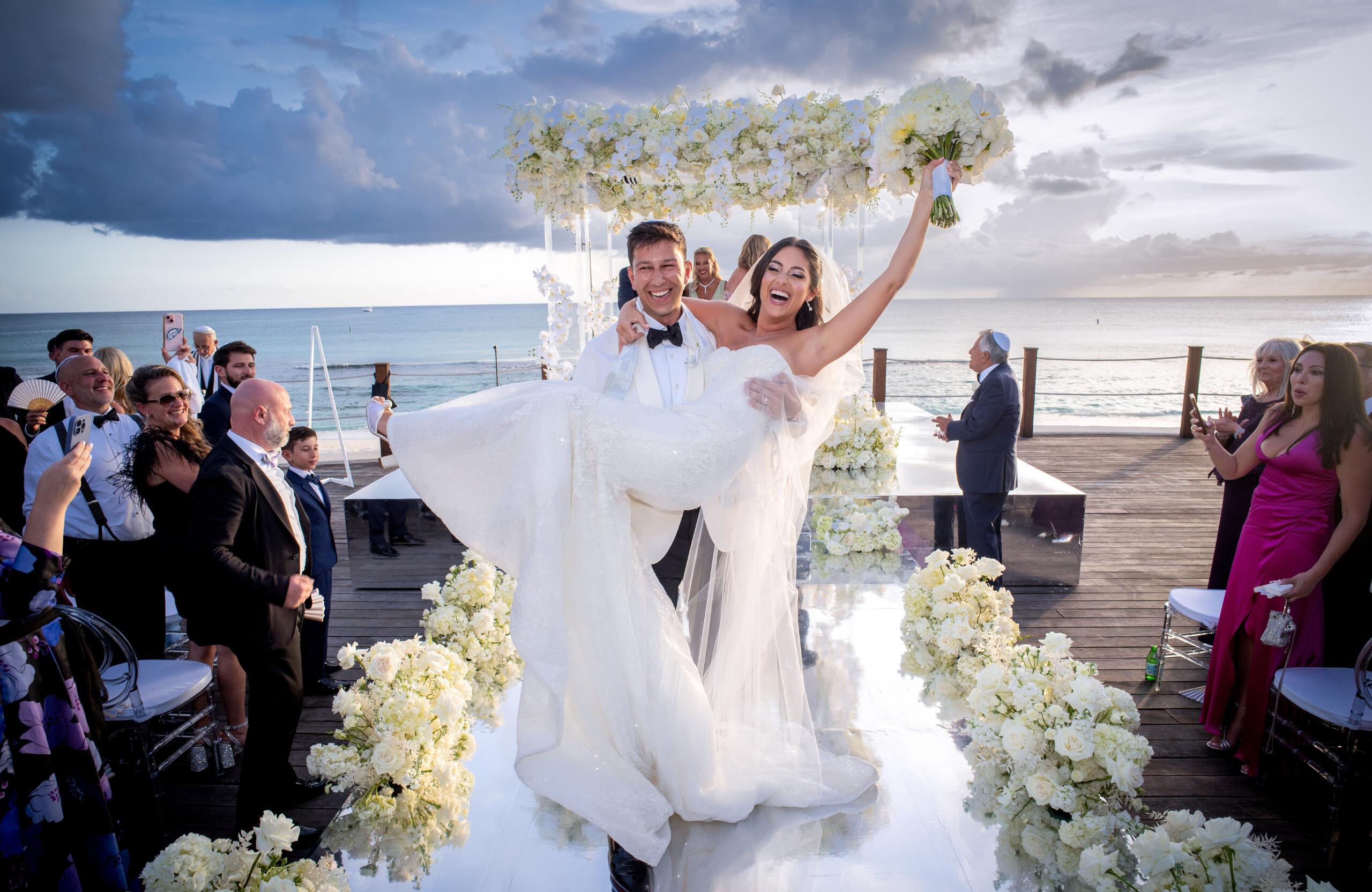 bride being carried by groom down wedding ceremony aisle