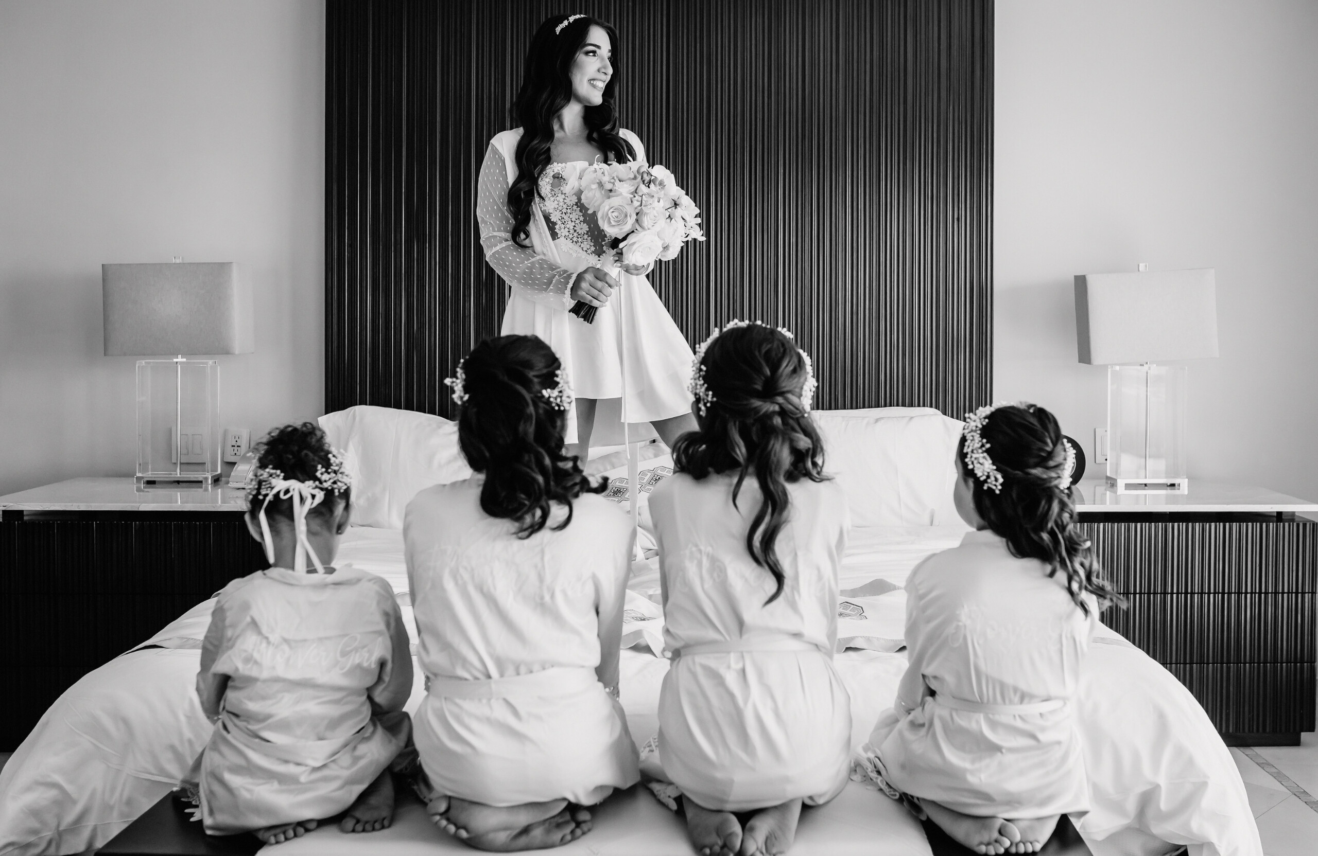 black and white photo of bride getting ready with flower girls