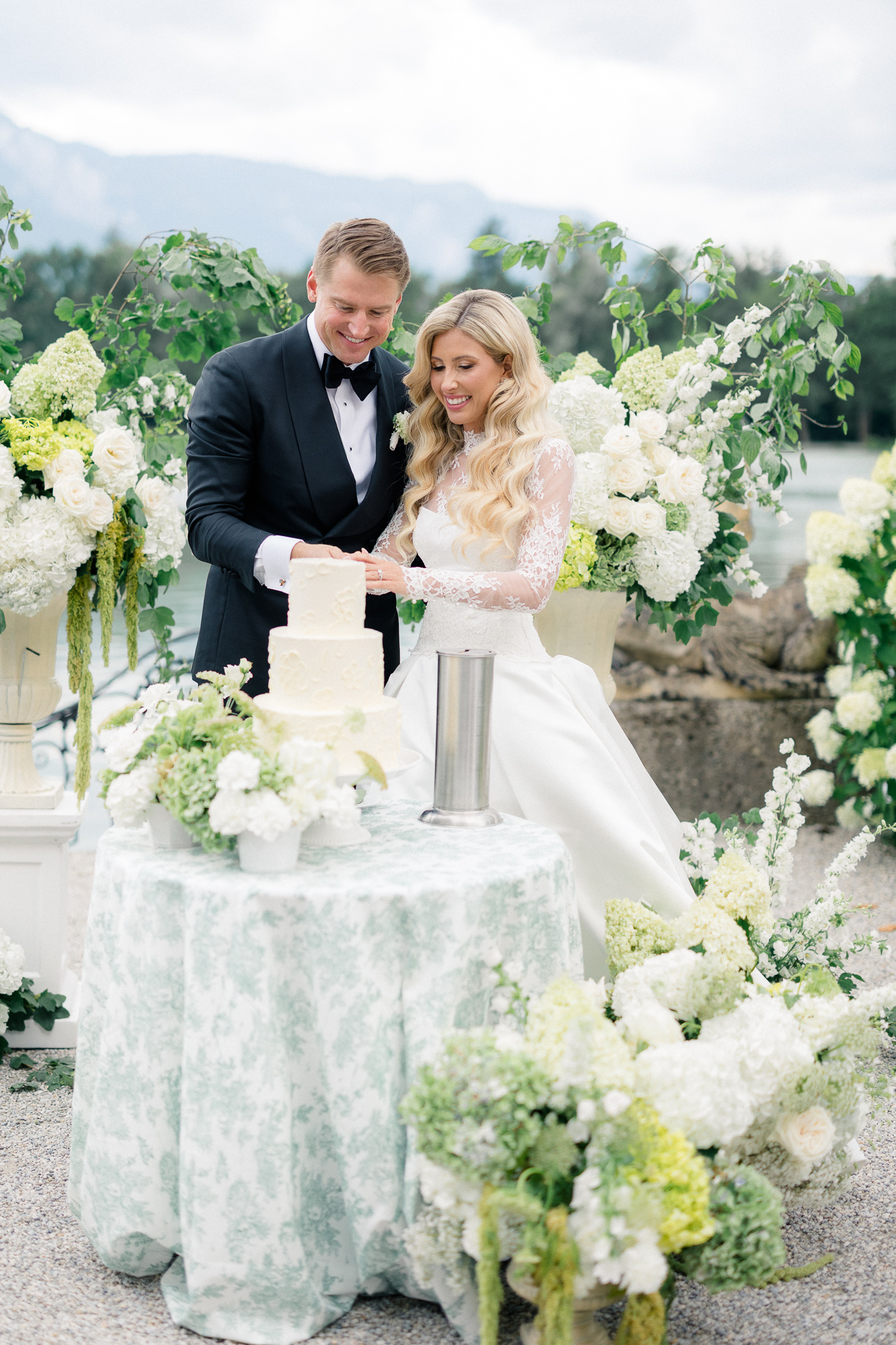 bride and groom wedding cake cutting by lake at Schloss Leopoldskron 